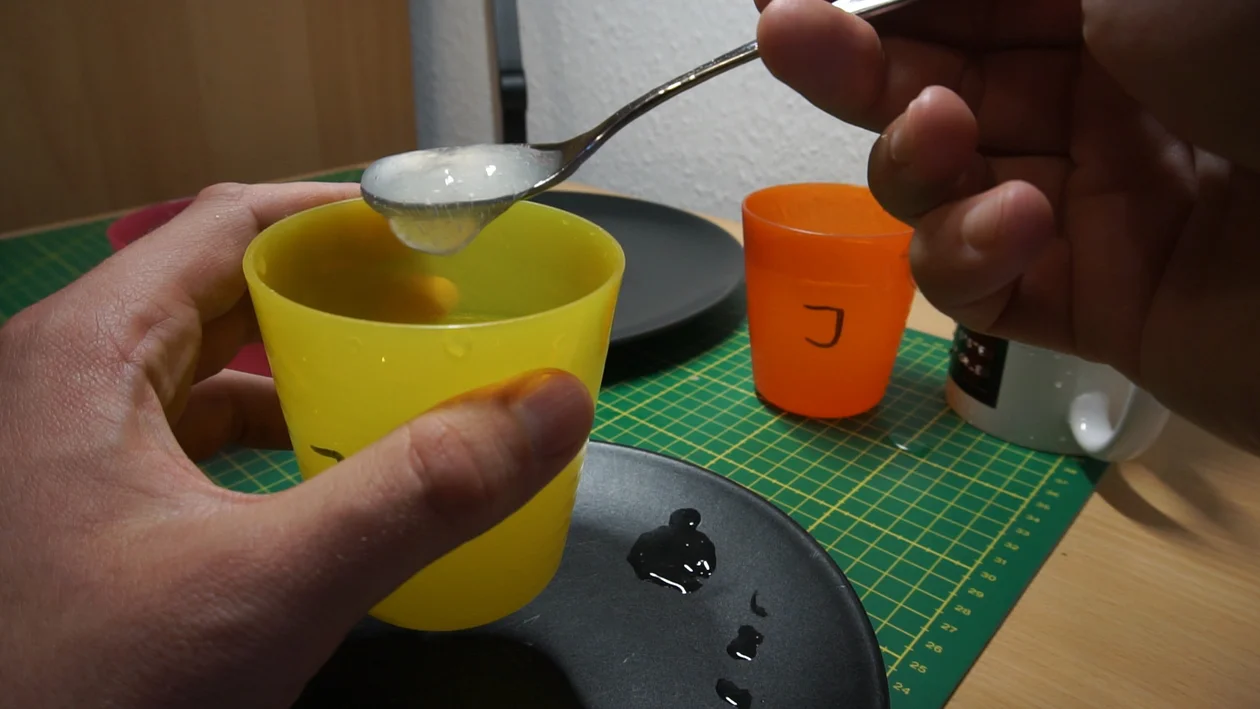 Carob bean and xanthan gum mixture in a cup, running of a spoon. Note the blob of gelatinous mixture hanging of the spoon before actually dropping.